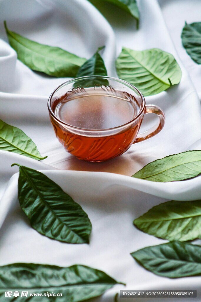 白绸上的茶杯与绿叶