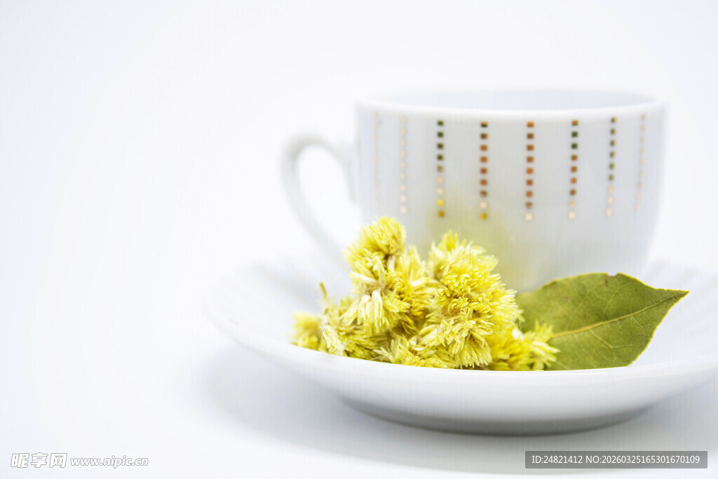 白杯旁的黄花朵与绿叶