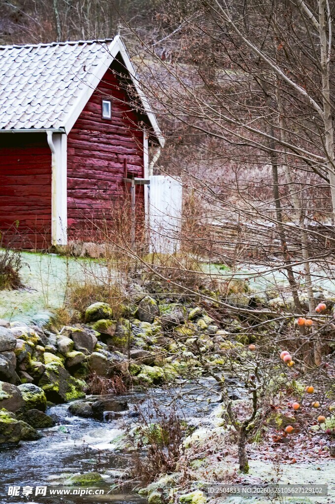 雪中小屋旁的潺潺溪流