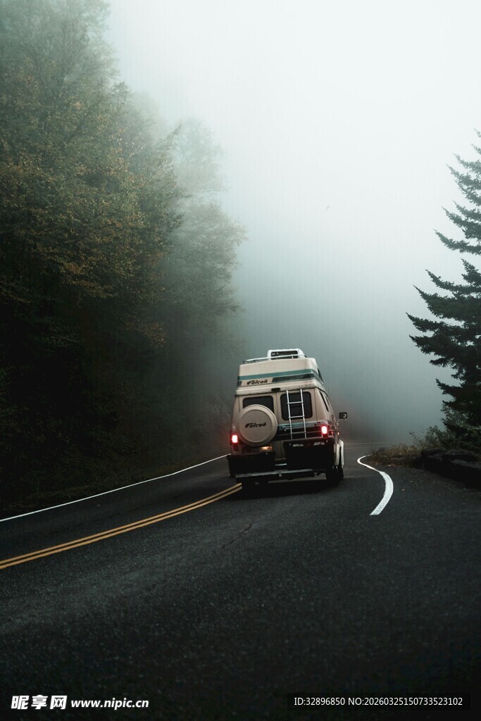 雾中公路上行驶的复古车辆