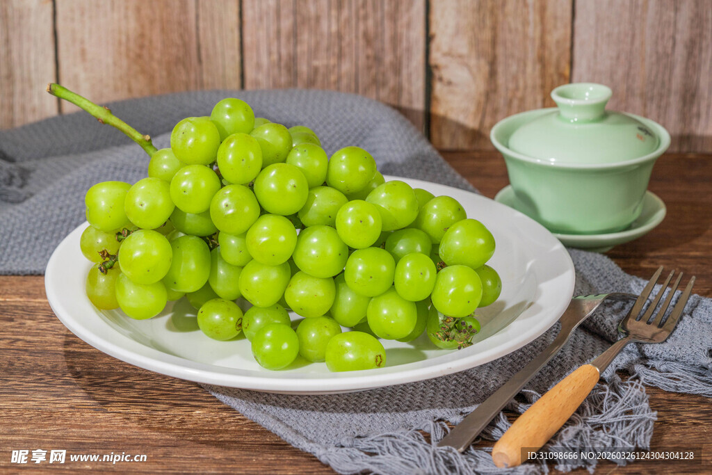 一盘鲜绿葡萄摆于木桌
