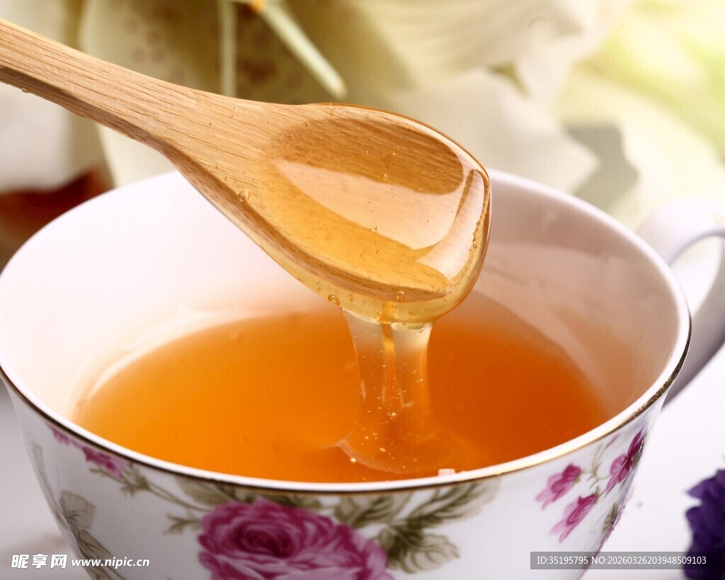 木勺舀蜂蜜入花纹茶杯