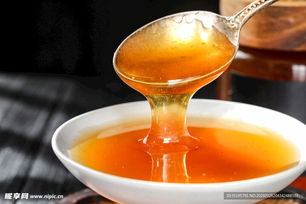 蜂蜜从勺中倾入白瓷碗中