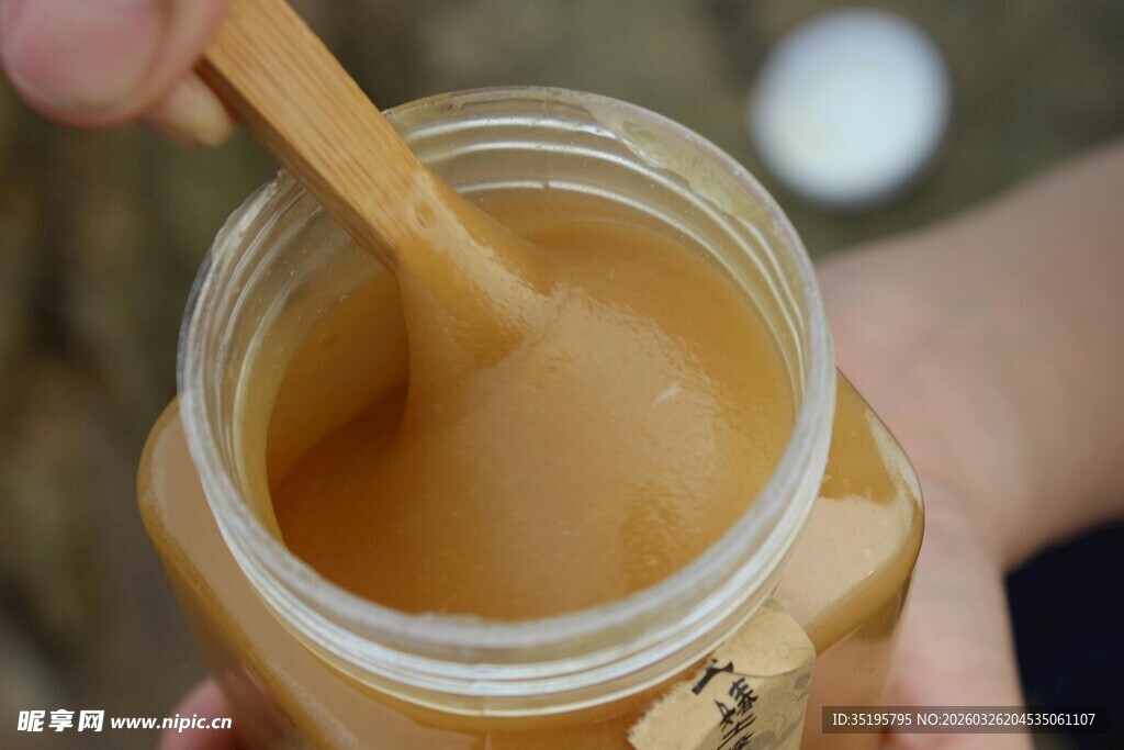 手持木勺舀取罐装蜂蜜