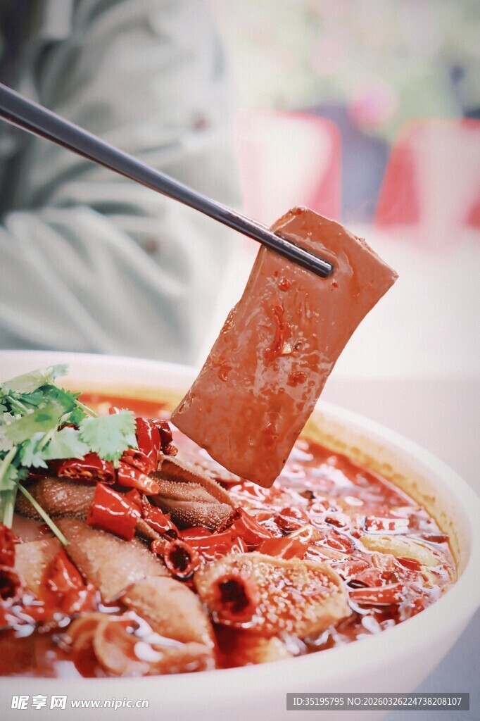 筷子夹起美味红油火锅食材