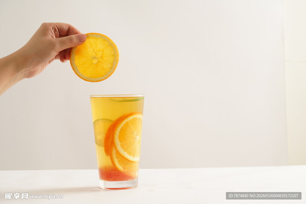 手放橙片入满杯橙汁