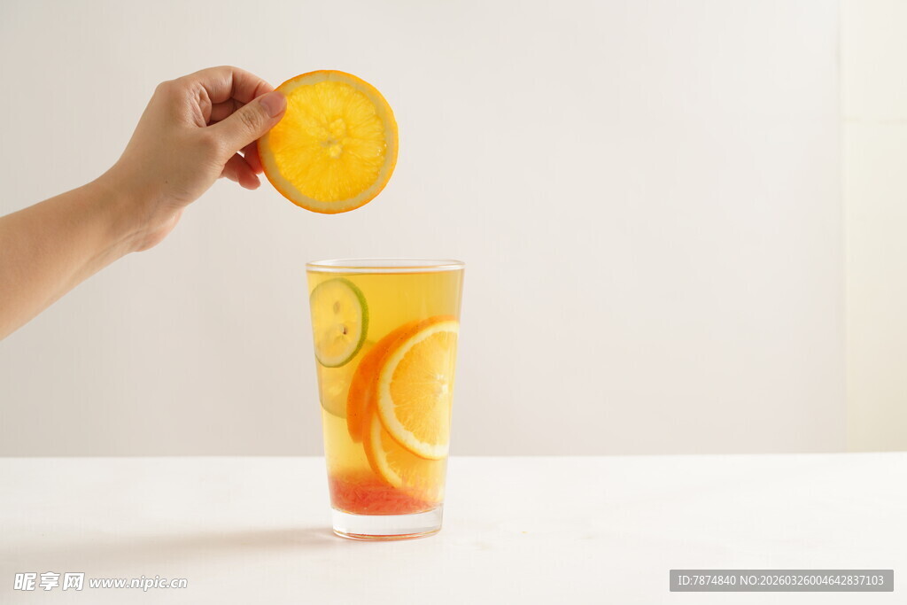 手挤橙子入满橙片的玻璃杯