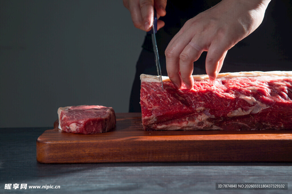 手切鲜牛肉于木砧板上