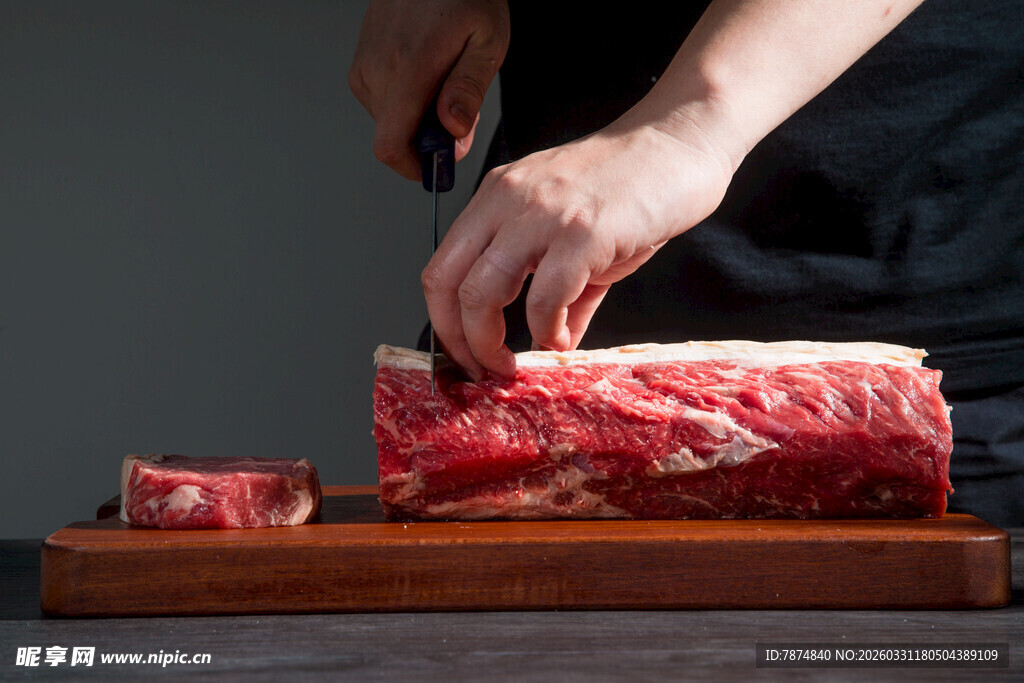 手切新鲜牛肉于木砧板上