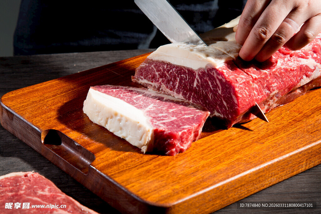 刀切新鲜牛排于木砧板上