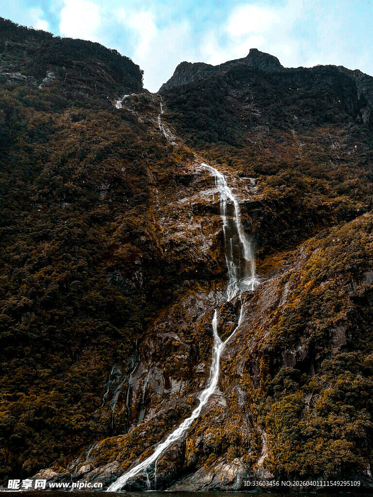 山间瀑布流淌于斑斓山坡