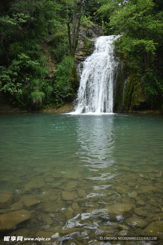 山间清澈瀑布下的碧绿潭水
