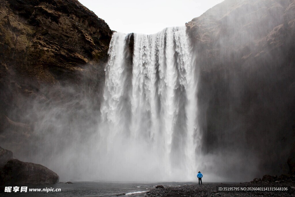 人立于壮观瀑布前景象