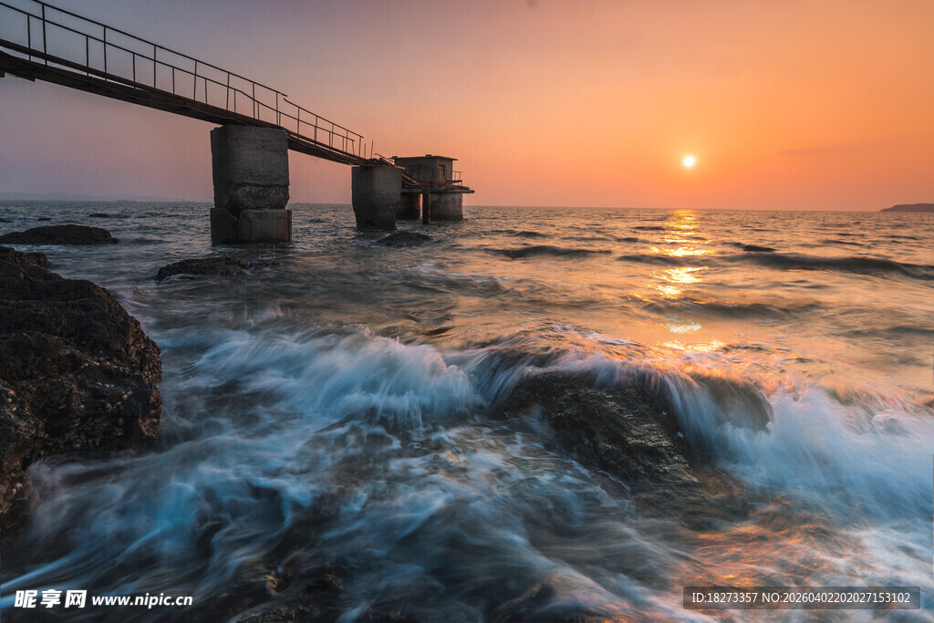 夕阳下海边栈桥与浪花