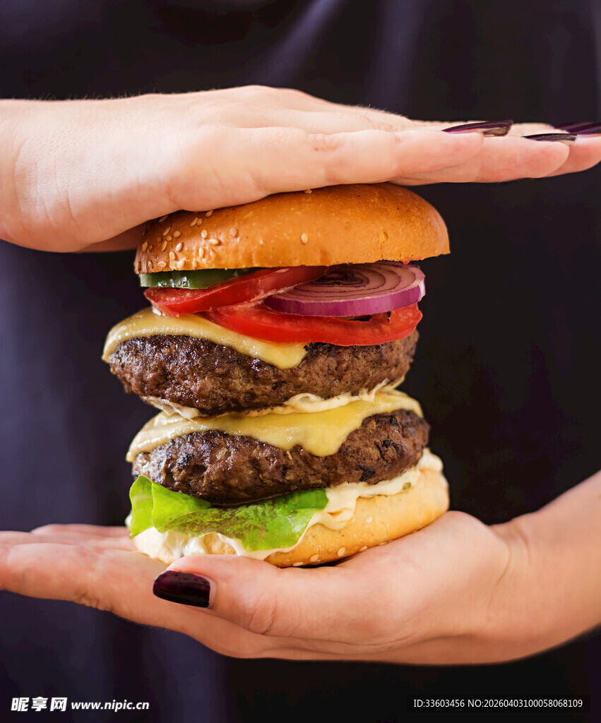 双手捧起的多层美味汉堡