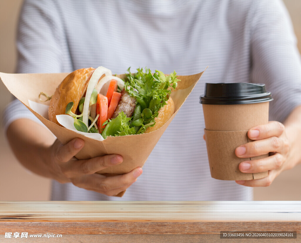 手持美味三明治与咖啡