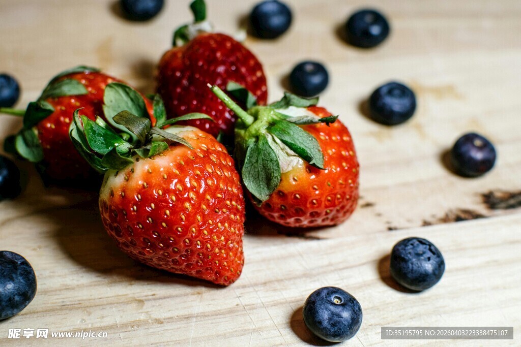 新鲜草莓与蓝莓摆放在木面