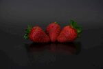 三颗鲜红草莓摆于黑底