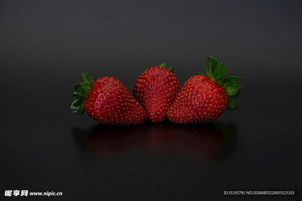 三颗鲜红草莓摆于黑底