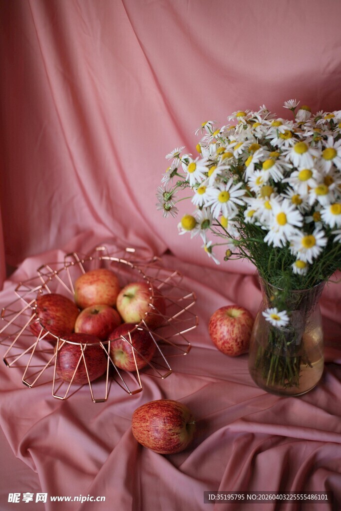 粉布上的苹果与雏菊插花
