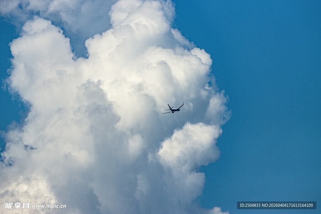 蓝天下飞机穿越大朵白云