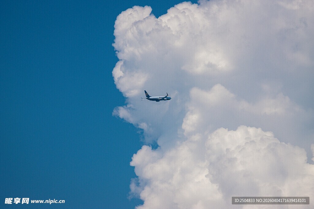 蓝天中飞机穿越大朵白云