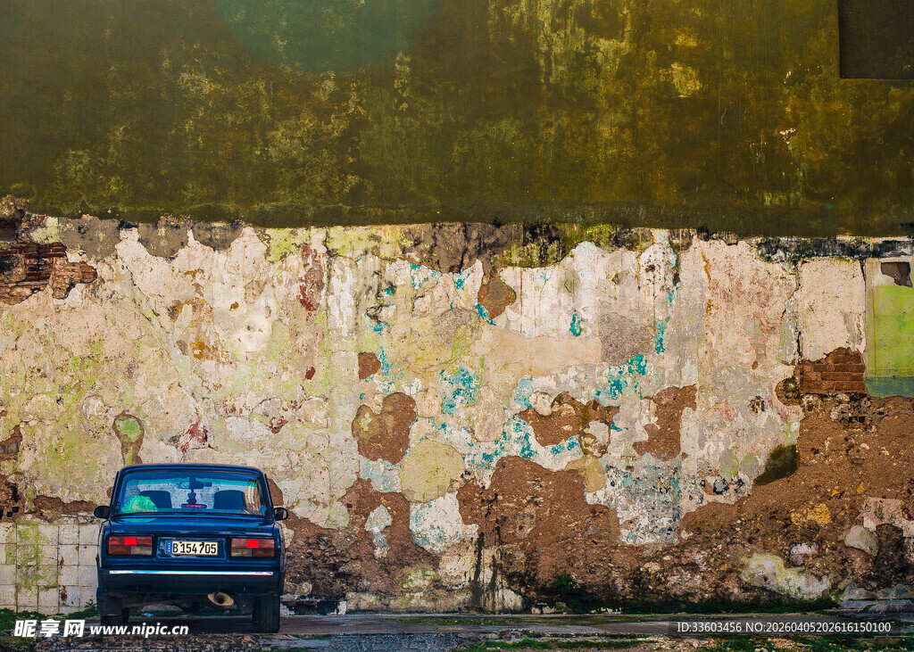 破旧墙前的蓝色汽车