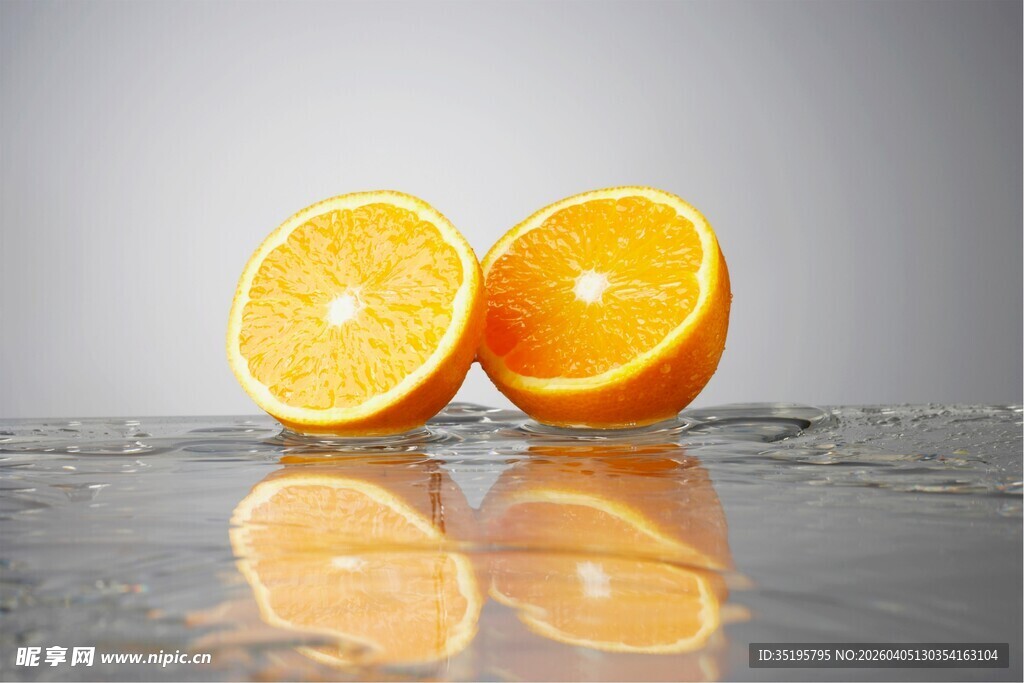 两半鲜橙置于反光表面
