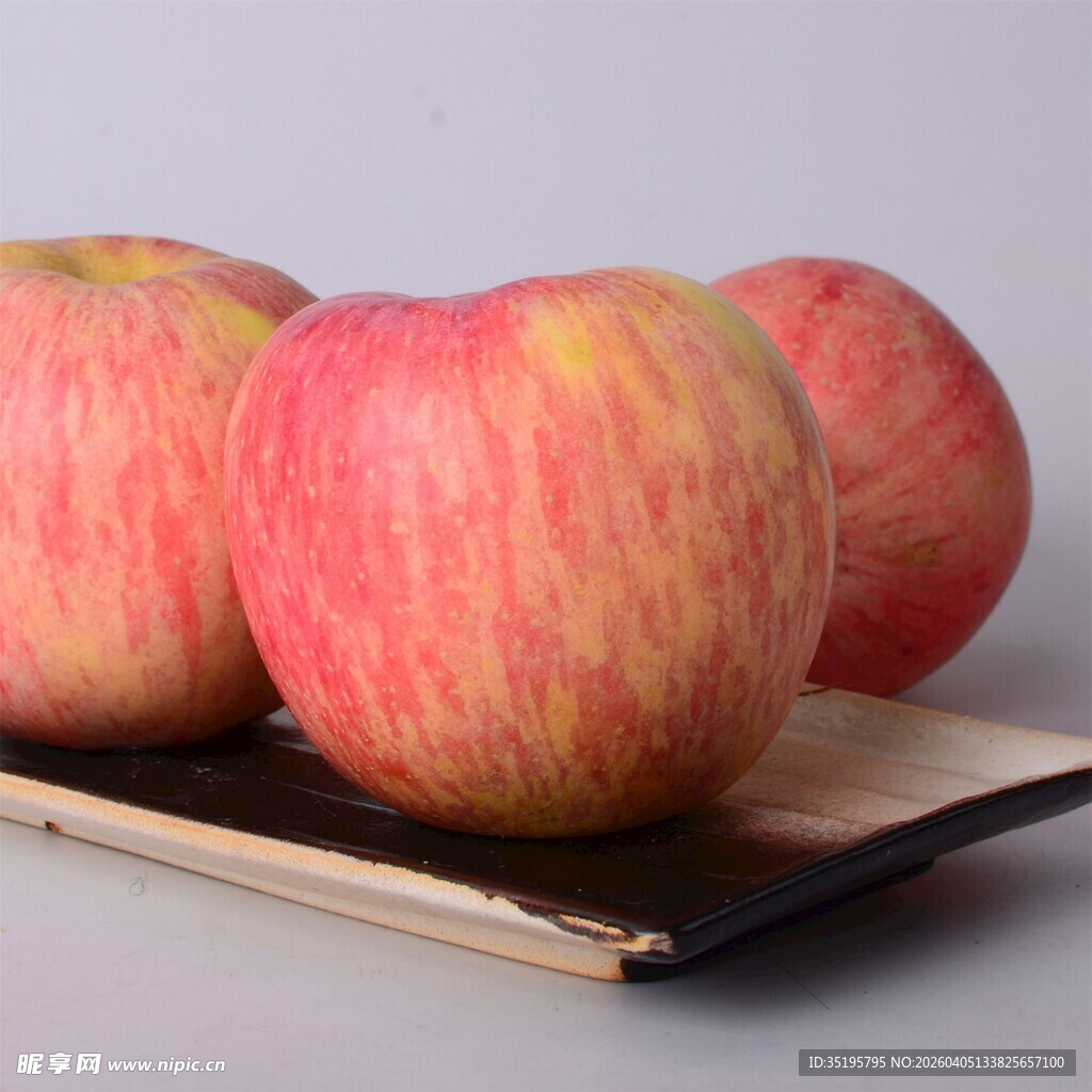 三个红苹果置于书本上