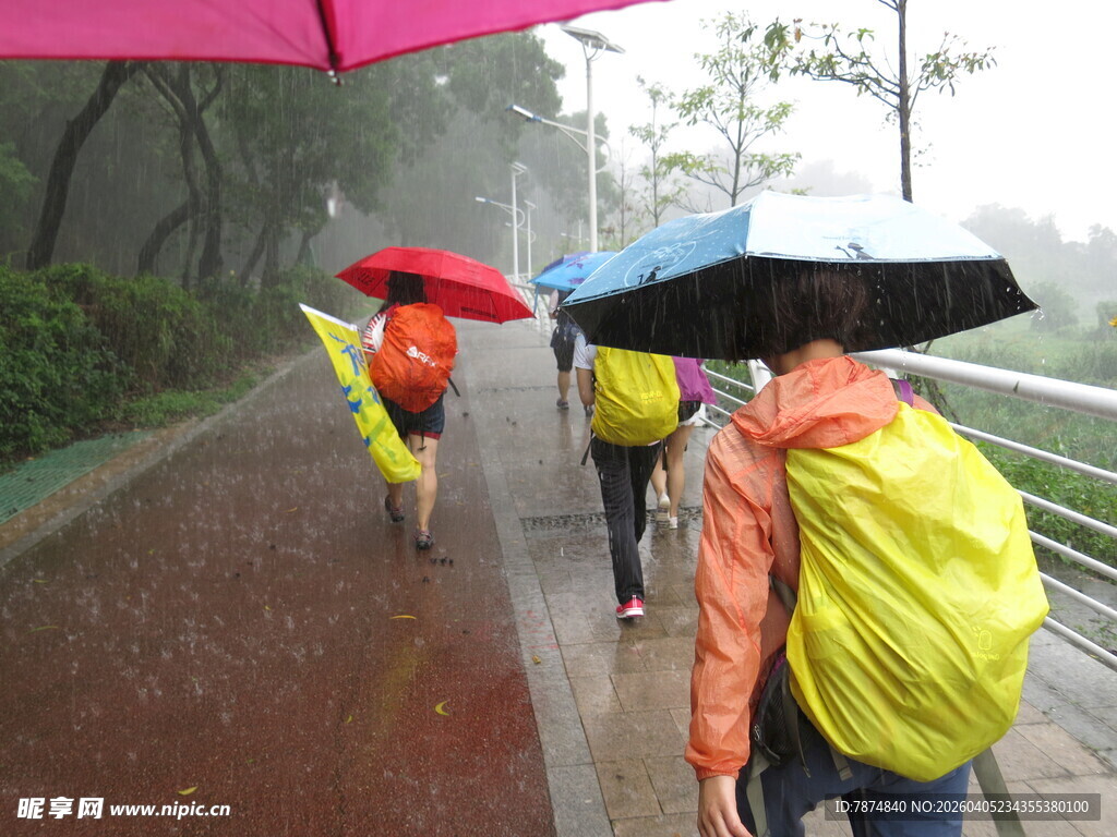 雨中行人撑伞穿雨衣前行