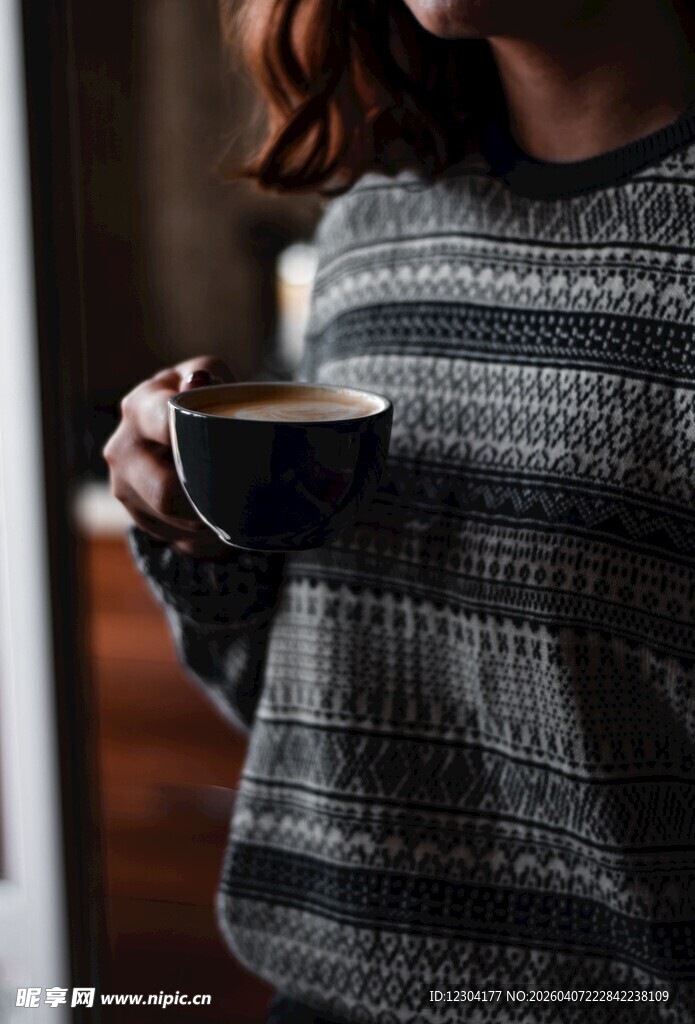 女子手持咖啡穿条纹毛衣