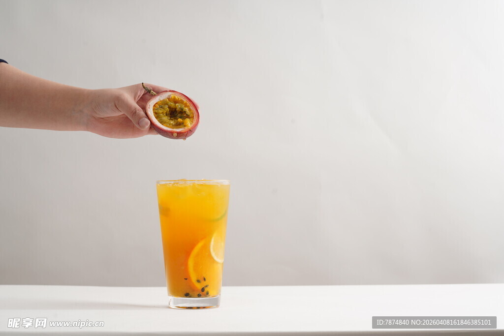 手挤百香果汁入满杯橙汁