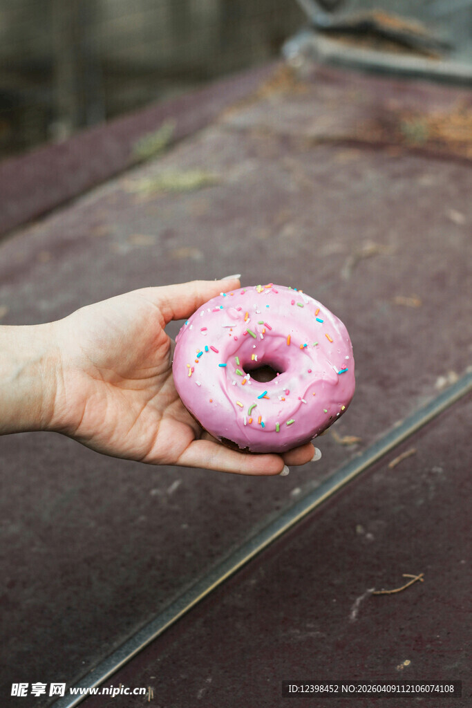 手持粉色甜甜圈特写