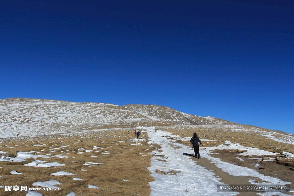 徒步者在雪覆山坡上行进