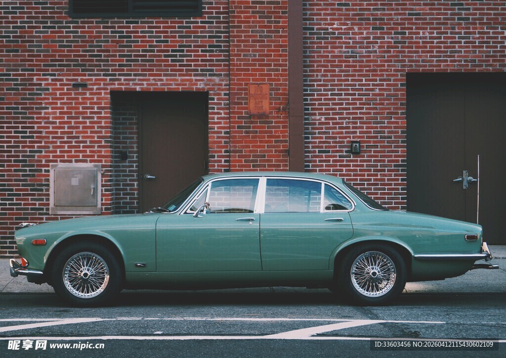 复古绿色轿车停于砖墙旁