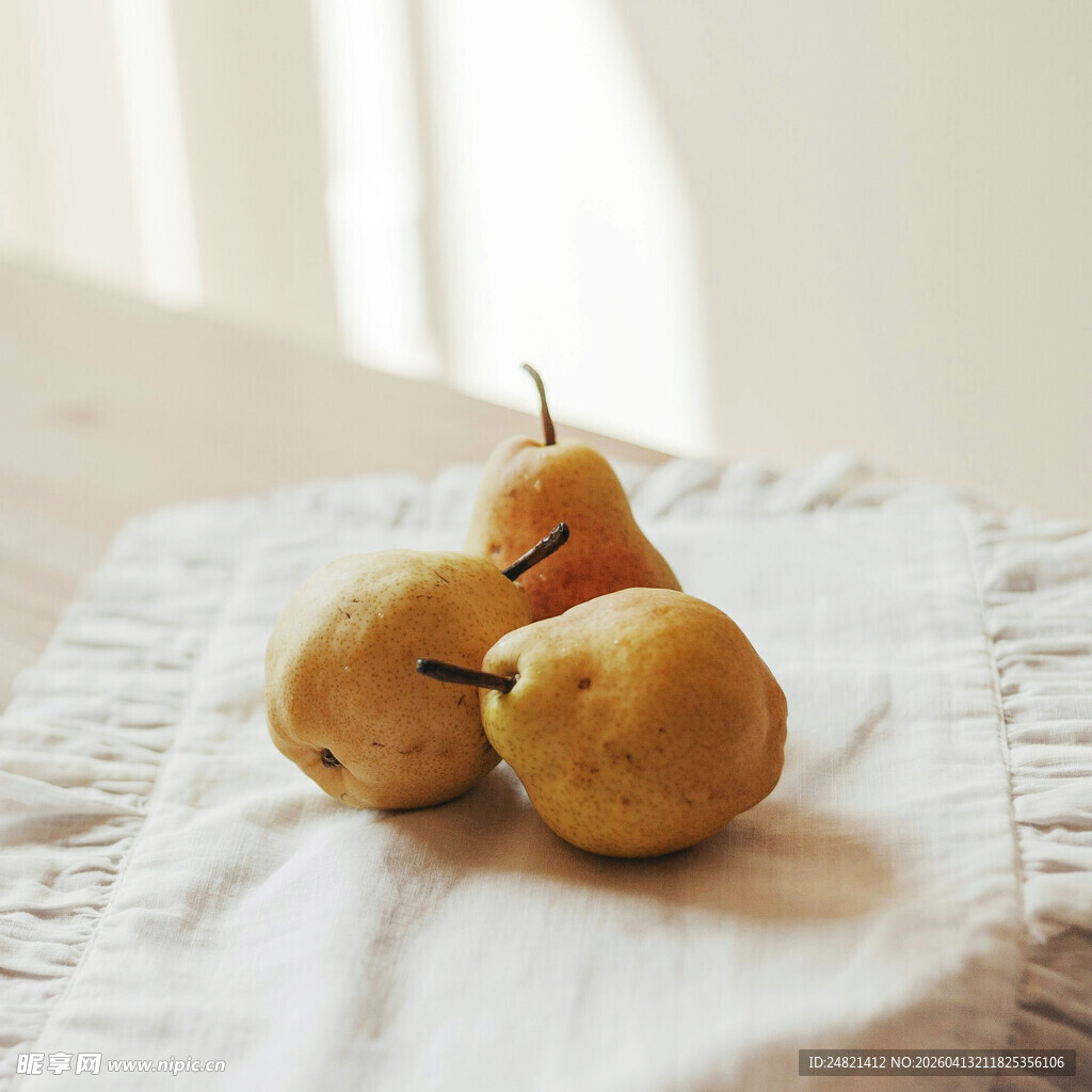 布上摆放的三颗新鲜梨子
