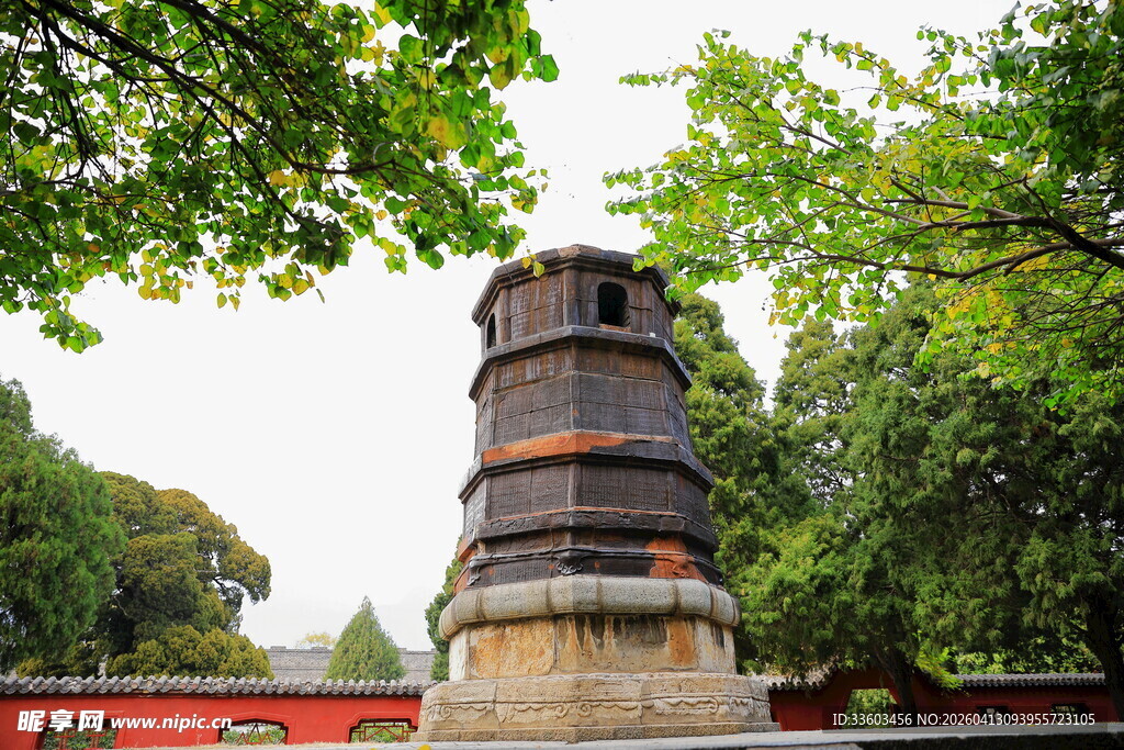 古塔立于绿树红墙间