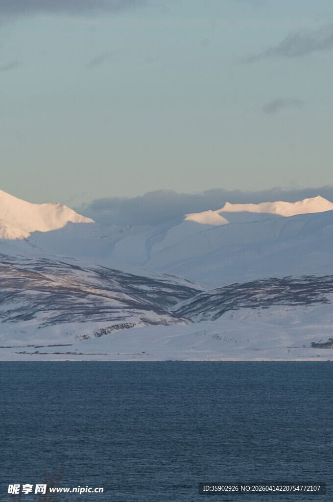 雪覆山峦旁的广阔蓝色水域