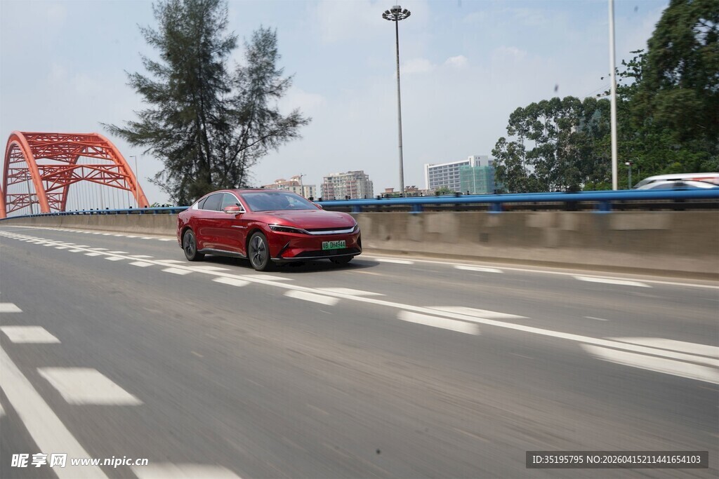 红色轿车行驶在宽阔道路上