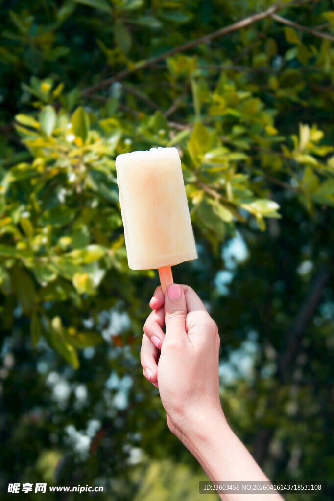 手举冰棍于绿意背景下