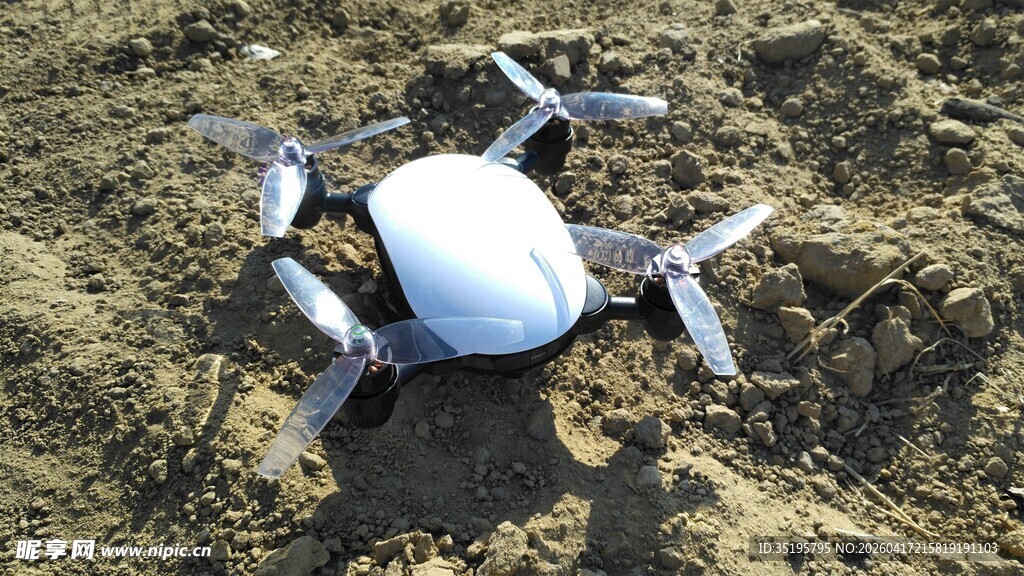 白色无人机停在泥土地上