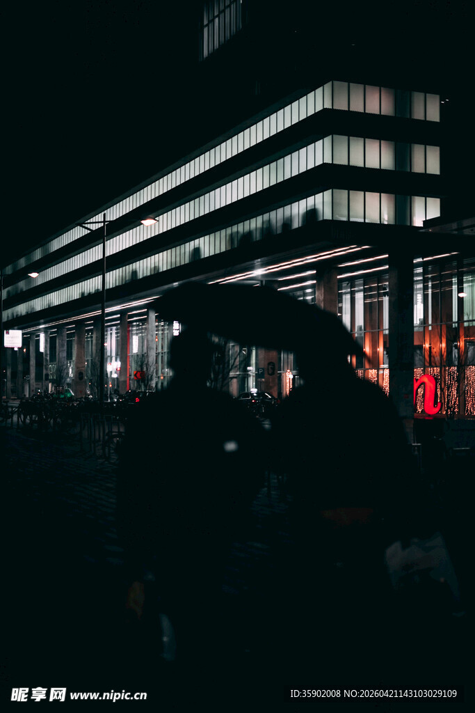 夜晚城市建筑下的行人身影