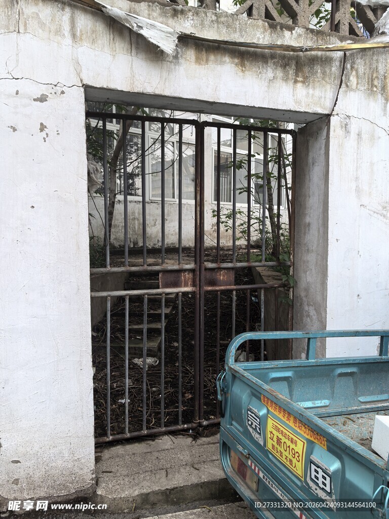 老旧铁门旁的蓝色小货车