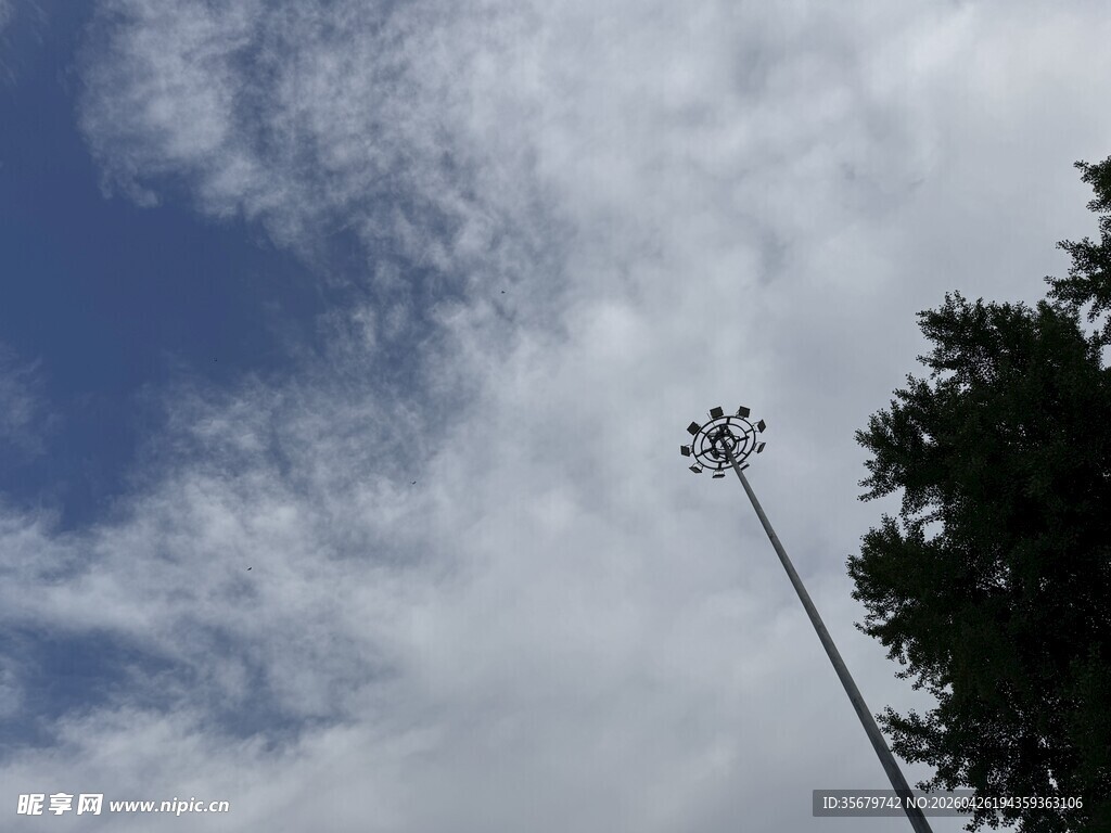 蓝天绿树间的高耸灯杆
