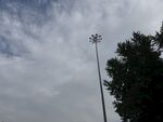 高耸灯杆旁的树木与天空