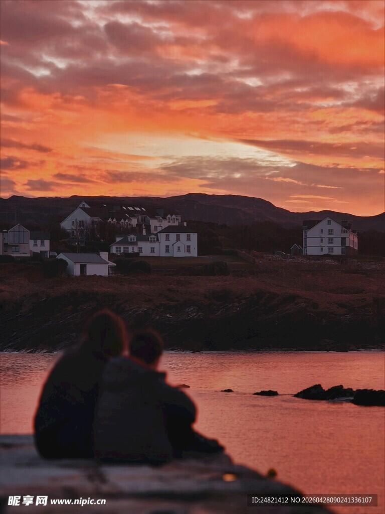 夕阳下情侣坐于湖畔赏景