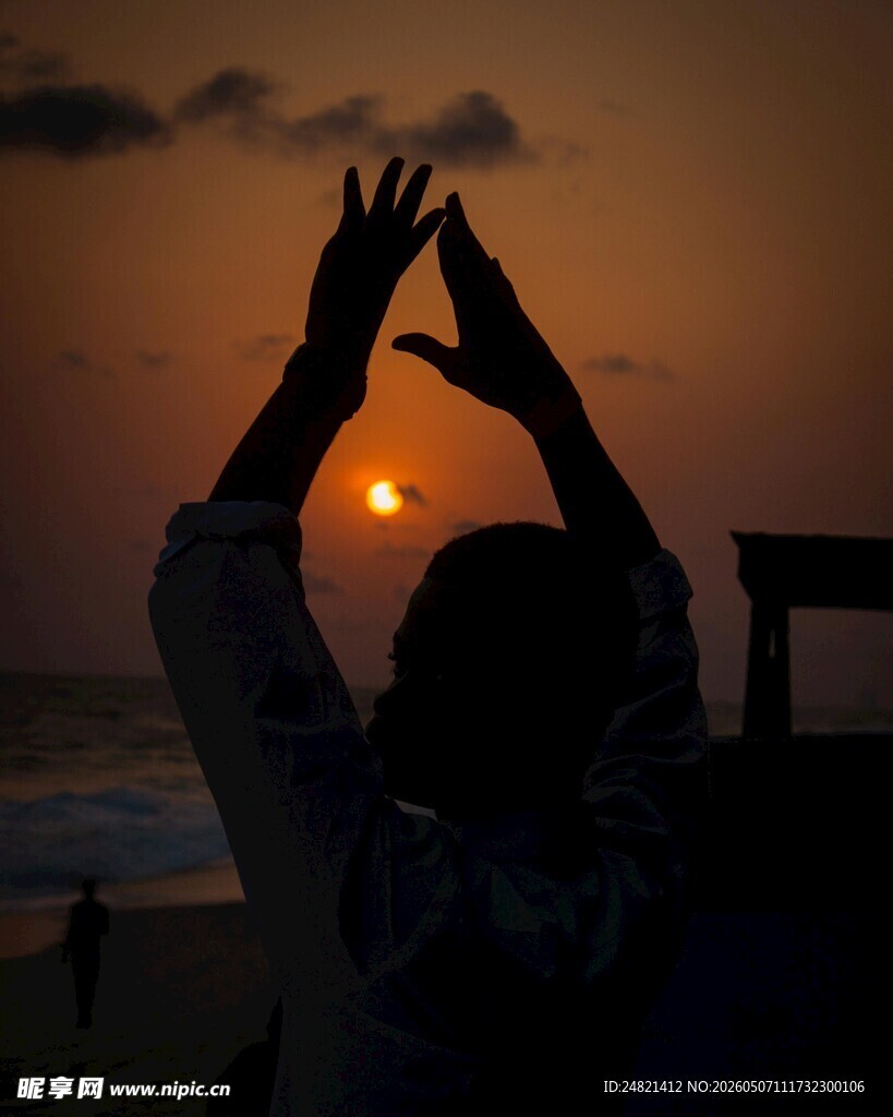 夕阳下海边的双手剪影