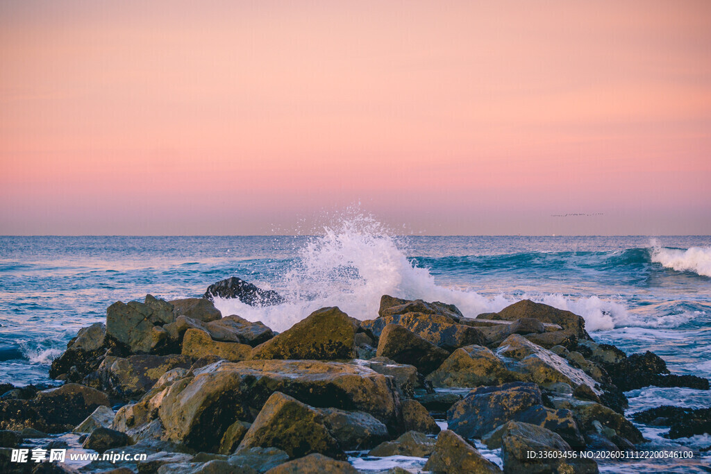 夕阳下海浪拍打礁石美景