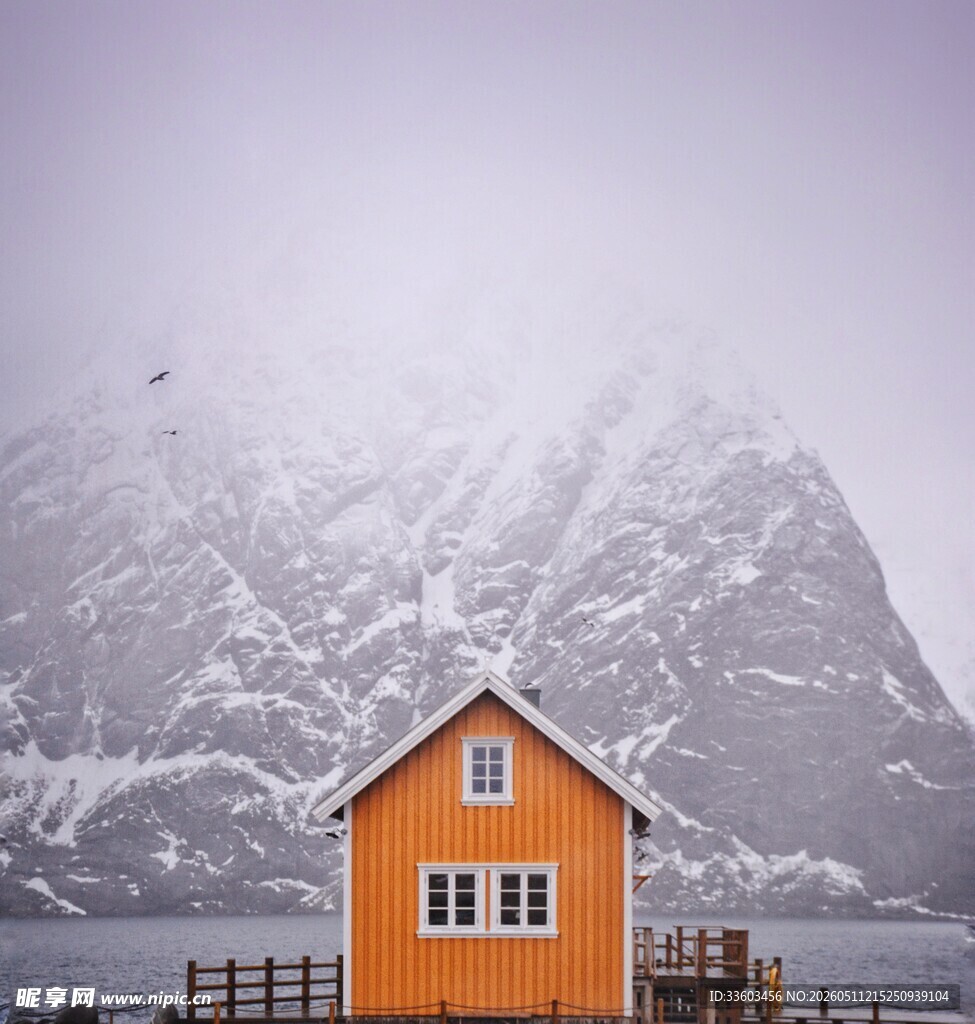 雪中山脚下的橙色小屋