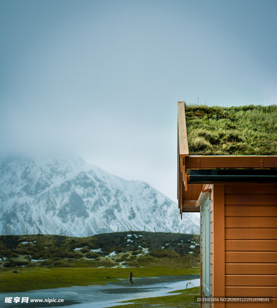 屋顶覆绿的小屋与雪山美景
